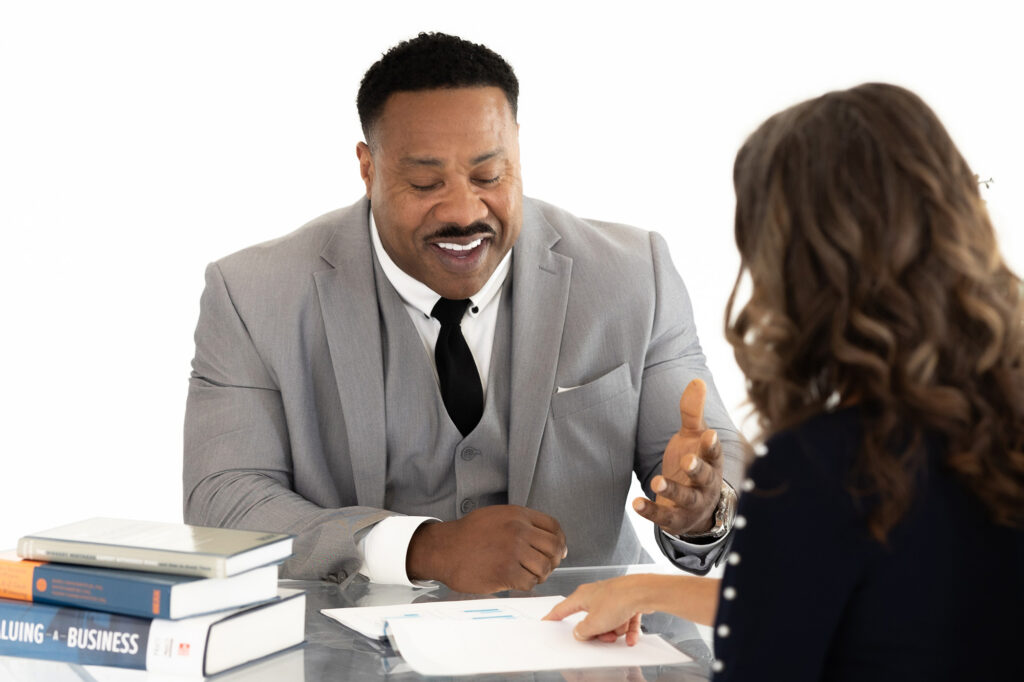 Financial advisor at McEntire Advisory, Specialized Accounting Services, discussing documentation across a desk with a client.