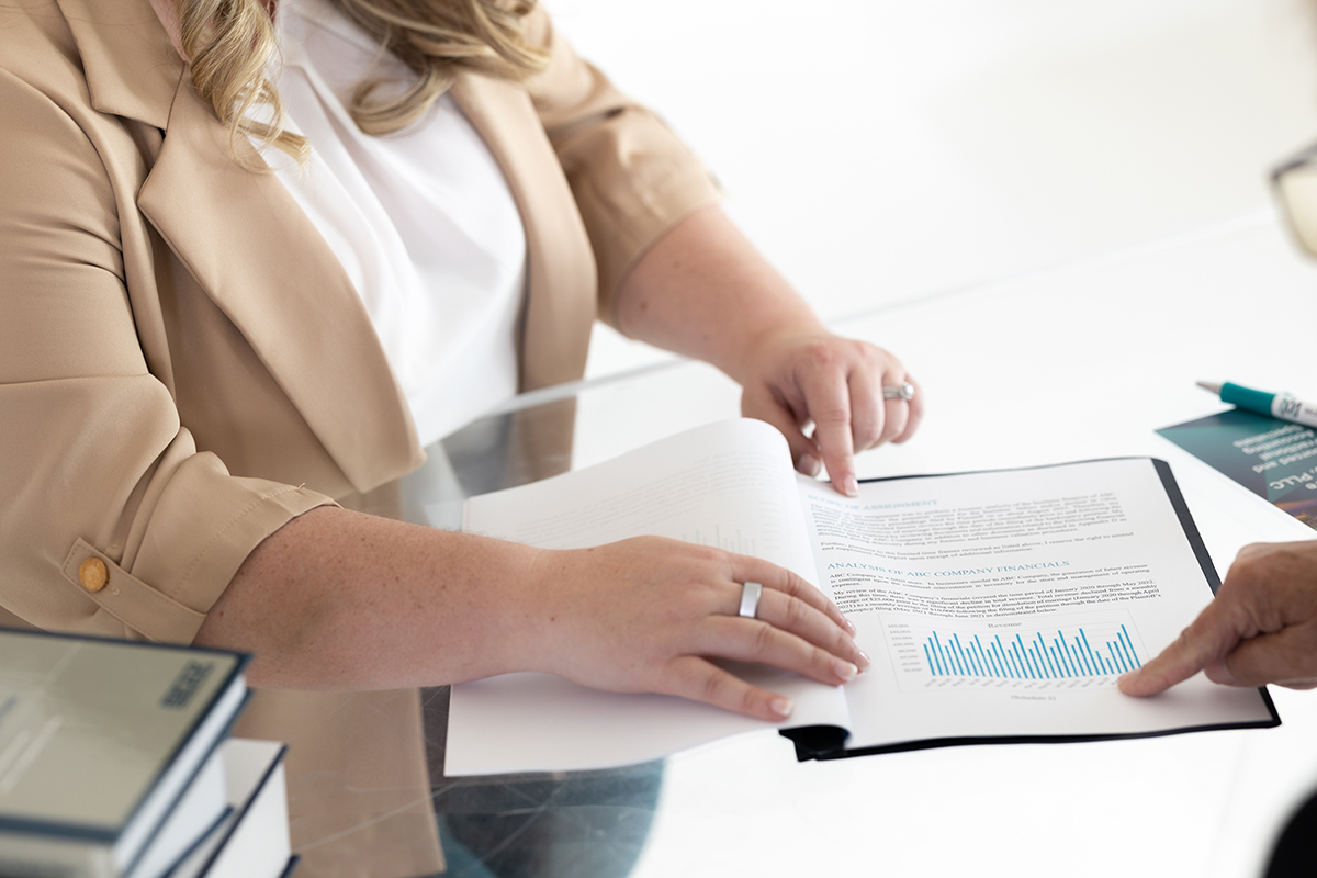 Two professionals review a printed financial report with a bar graph, illustrating business valuation services during estate planning.